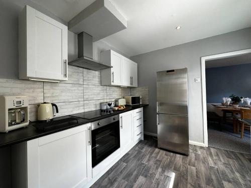 a kitchen with white cabinets and a stainless steel refrigerator at GREAT LOCATION! 4 bed house with garden & parking - Parkstone House in Parkstone
