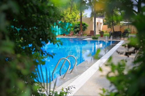 una piscina con agua azul, mesas y sillas en Evoma, en Bangalore