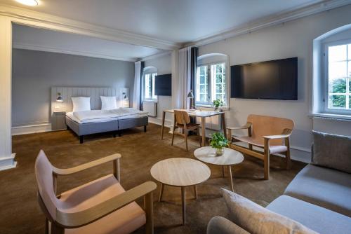 a hotel room with a bed and tables and chairs at Comwell Bygholm Park in Horsens