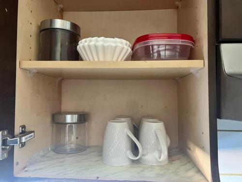a shelf with bowls and other dishes in a drawer at Flowealth Suites - Private Rooms Near West Edmonton Mall in Edmonton