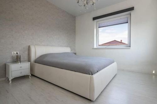 a white bedroom with a bed and a window at VoVoHouse in Ginduliai