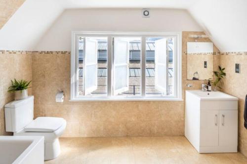 La salle de bains est pourvue de toilettes et d'une fenêtre. dans l'établissement Three-Storey, Renovated 1890s Heritage Home in Spitalfields Market, à Londres