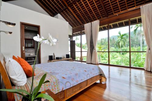 a bedroom with a bed and large windows at Villa Rumah Isah in Candidasa