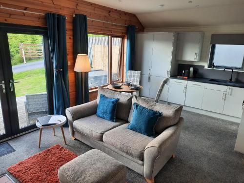 a living room with a couch and a kitchen at Kinnaird Woodland Lodges in Pitlochry