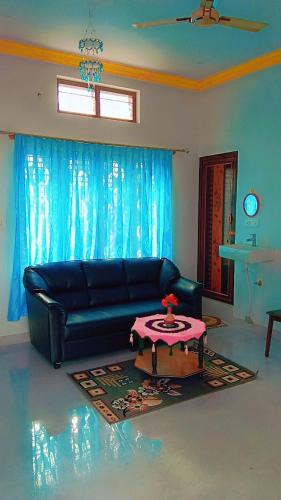 a living room with a black couch and a table at Kailash Guest Home in Mysore
