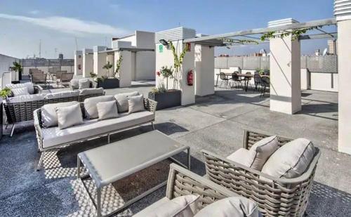 a patio with couches and tables on a roof at Livensa Living Studios Valencia Marina Real in Valencia