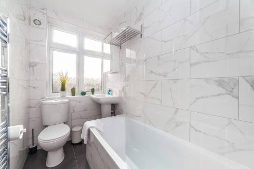 a white bathroom with a tub and a toilet at 2-Bedroom Apartment in Greater London: Explore and Relax in Enfield