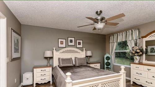 - une chambre avec un lit blanc et un ventilateur de plafond dans l'établissement Patio Villa Near Sumter Landing, à The Villages