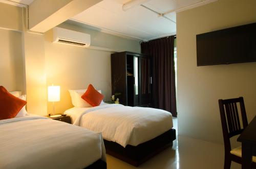 a hotel room with two beds and a flat screen tv at Annex Lumpini Bangkok in Bangkok