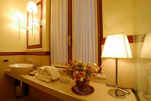 a bathroom with a sink and a vase of flowers on a counter at Zunica Ospitalità dal 1880 in Civitella del Tronto