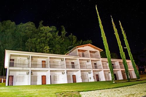 a large white building at night with palm trees at Hotel Fazenda M1 in Águas de Lindóia