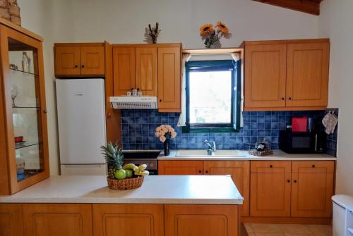 a kitchen with wooden cabinets and a bowl of fruit on the counter at Tholos Alexandra's Beachfront House in Kavoúsion