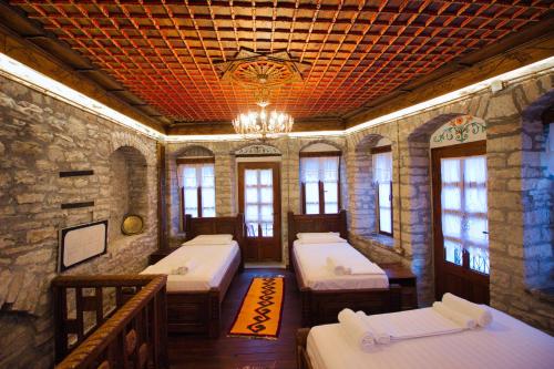 een kamer met 4 bedden en een kroonluchter bij Duplex Apartment KANDILE in Gjirokastër
