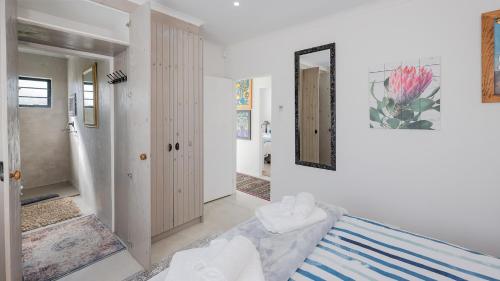 ein weißes Zimmer mit einem Bett und einem Spiegel in der Unterkunft Oceans Cottage Struisbaai in Struisbaai
