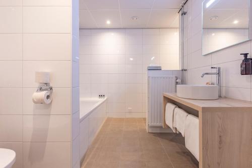 a white bathroom with a sink and a tub at Fletcher Hotel-Restaurant De Scheperskamp in Lochem