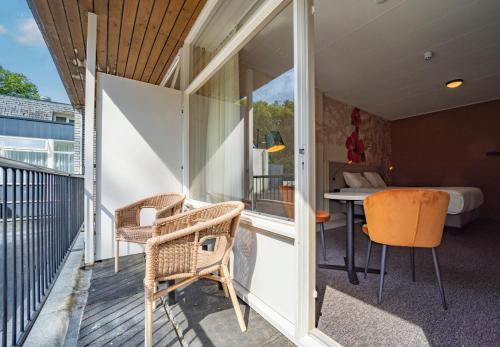 a room with a balcony with a bed and chairs at Fletcher Hotel-Restaurant De Scheperskamp in Lochem