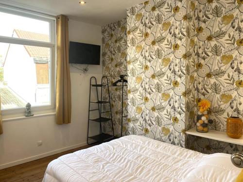 1 dormitorio con cama y pared de flores en Le P'tit Cocon en Calais