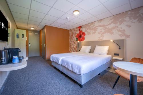 a hotel room with a large bed and a table at Fletcher Hotel-Restaurant De Scheperskamp in Lochem
