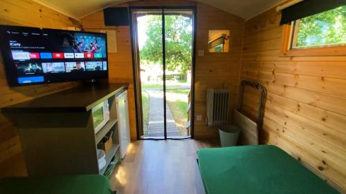 a living room with a television and a sliding glass door at Orchard Hideaways in Penrith