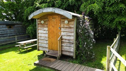 a wooden out house with a door in the grass at Orchard Hideaways in Penrith