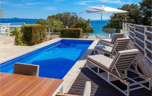 a swimming pool with chairs and an umbrella at Villa Calla in Petrcane