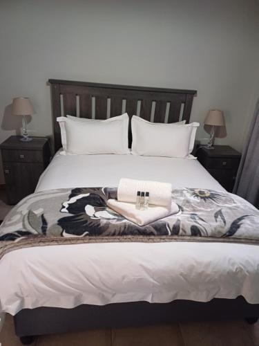 a bedroom with a bed with two towels and two lamps at Augrabies De Oude Stoor Guesthouse in Augrabies