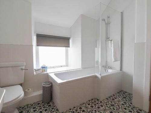 a bathroom with a tub and a toilet and a window at Ffriddoedd in Llanfairfechan