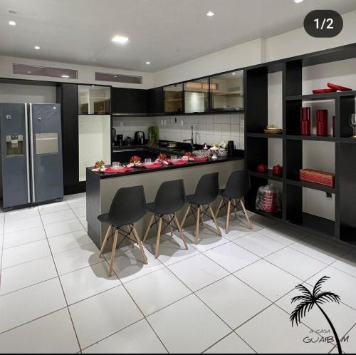 una cocina con armarios negros y una barra con sillas en Casa LUXO Guaibim, en Guaibim