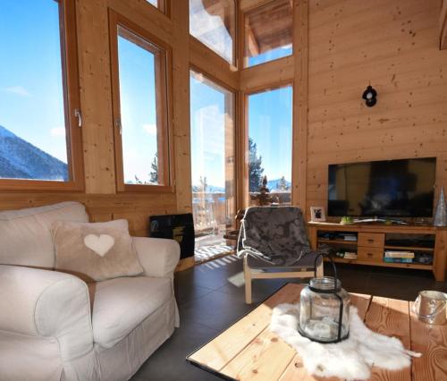 a living room with a couch and a tv and windows at Chalet Loan in Montgenèvre