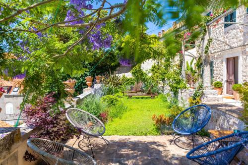 un patio con 3 sillas y un jardín con flores púrpuras en Villa Ani apartment Ariel, en Dubrovnik