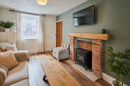 a living room with a fireplace and a tv on a wall at Church View Cottage & Secret Garden, Matlock - Now Hosted by StayHostSave in Matlock