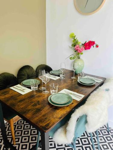 a wooden table with plates and glasses and a vase of flowers at Heerlijk appartement Centrum Breda en restaurant! in Breda