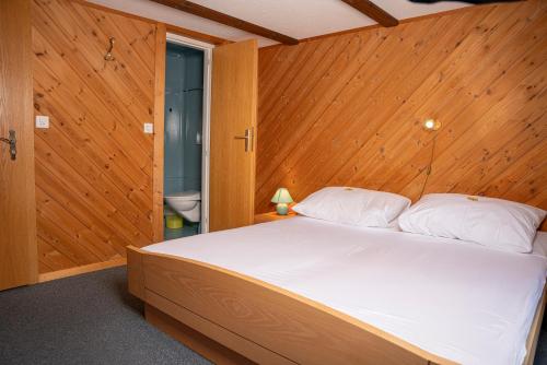 a bedroom with a bed with a wooden wall at Alte Bock 2.0 in Grächen