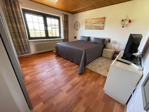 Schlafzimmer mit einem Bett und einem Flachbild-TV in der Unterkunft Fewo Zum Wohlfühlen in Hemmoor