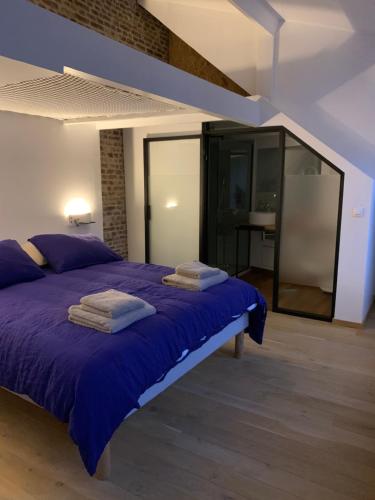 - une chambre avec un lit violet et des serviettes dans l'établissement galerie jacqueline storme, à Lille