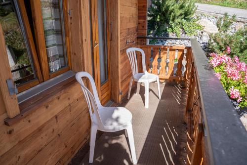 two white chairs sitting on the porch of a house at Alte Bock 2.0 in Grächen