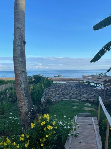 a pathway with a tree and a bench and the ocean at Agoho Resort in Mambajao