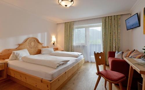 Schlafzimmer mit einem Bett, einem Schreibtisch und einem Fenster in der Unterkunft Pension Sunnbichl in Going