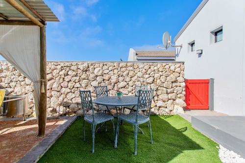 a table and chairs in a yard with a stone wall at Dunes, Waves and Shells - Self Catering Units Langebaan in Langebaan