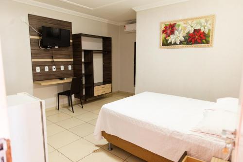 a bedroom with a bed and a desk and a television at Pôr do Sol Hotel in Santarém