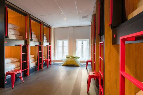 um quarto com muitos beliches e cadeiras vermelhas em City Trip Hostels Zaandam-Amsterdam em Zaandam