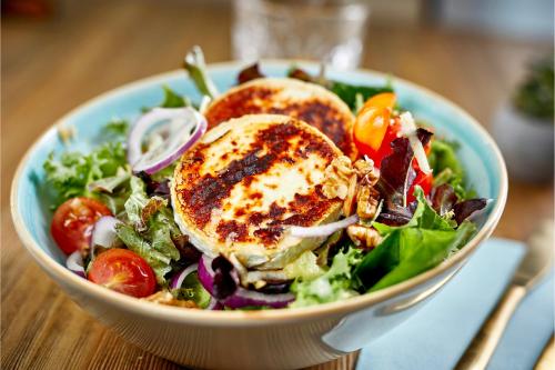 a bowl of salad with a chicken sandwich on top at E1 Suites & Spa aparthotel style - Gym & Spa in Gibraltar