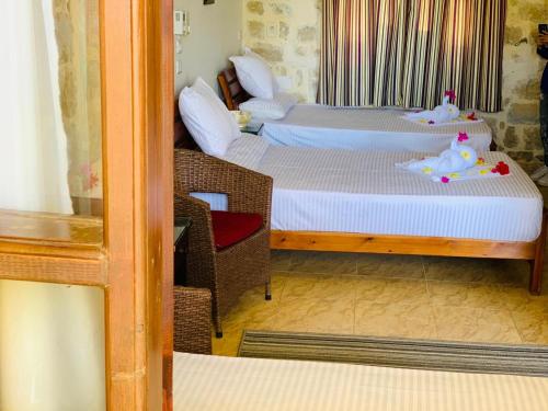 a room with two beds and a chair in it at palm shadow resort in Tunis