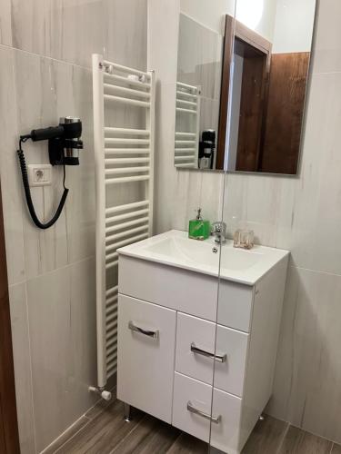 uma casa de banho com um lavatório branco e um espelho. em PENSIUNEA KONFORT em Borsa