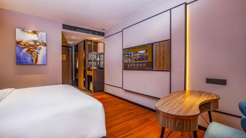 FUGO Hotel Samarinda في ساماريندا: غرفة نوم بسرير ابيض وطاولة خشبية