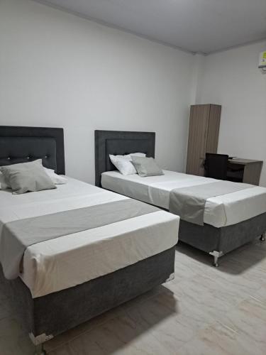 - deux lits assis l'un à côté de l'autre dans une pièce dans l'établissement HOTEL URDANETA NEIVA, à Neiva