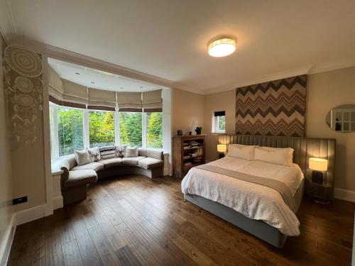Edwardian Manor near Glasgow City with HEATED POOL & HOT TUB في Giffnock: غرفة نوم بسرير واريكة ونافذة