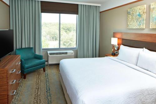 a hotel room with a bed and a chair and a window at Hilton Garden Inn Boston/Marlborough in Marlborough