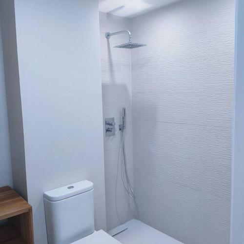 a white bathroom with a shower and a toilet at Apartamento Luz in Chiclana de la Frontera