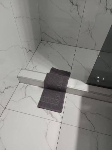 a black towel sitting on a white tiled floor at Cuza 21 in Brăila
